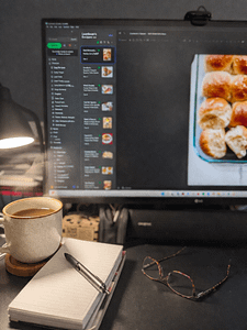 Weekly meal planning setup with Evernote open on a computer, notepad, pen, and glasses on a desk