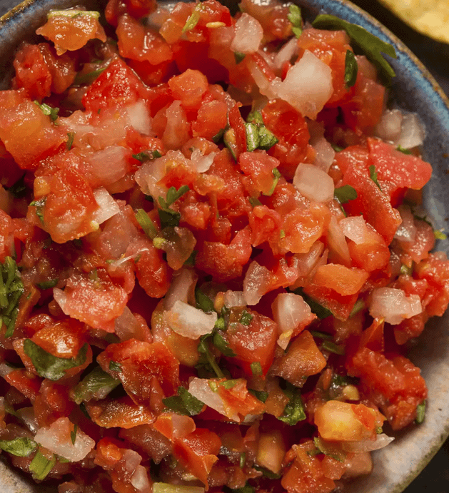 A bowl of chunky homemade salsa with diced tomatoes, onions, and cilantro, showing fresh texture and vibrant colors.