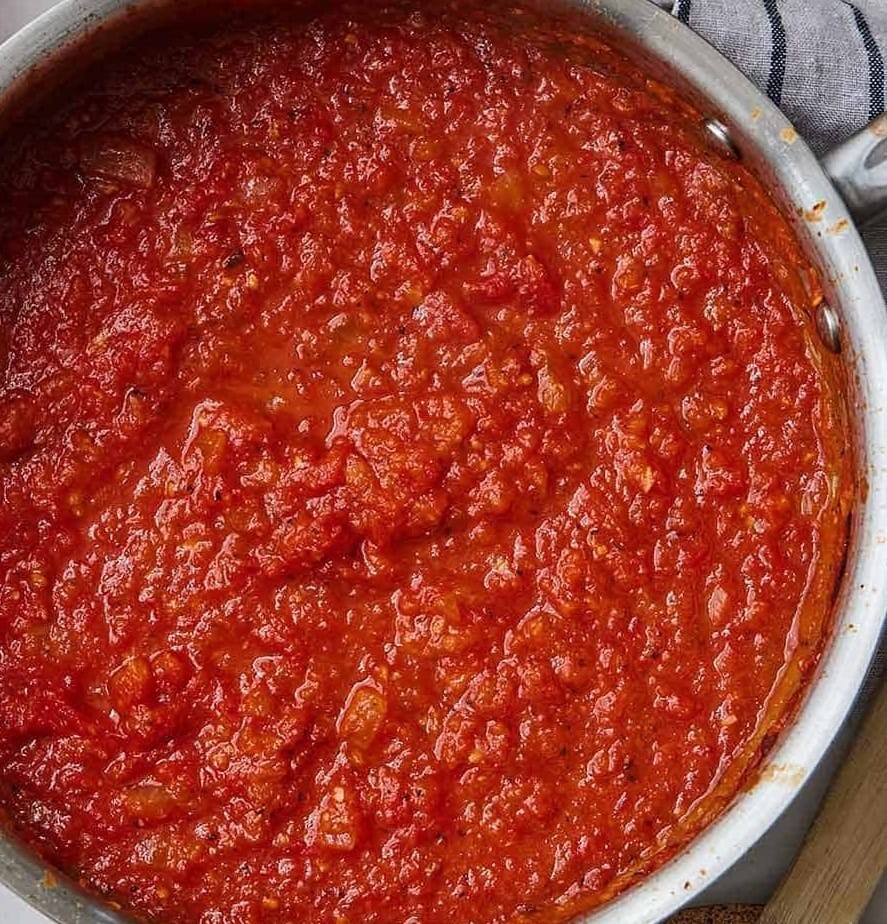 Simmering pot of homemade tomato sauce made with crushed tomatoes, garlic, onions, and olive oil—rich, rustic, and perfect for pasta or lasagna