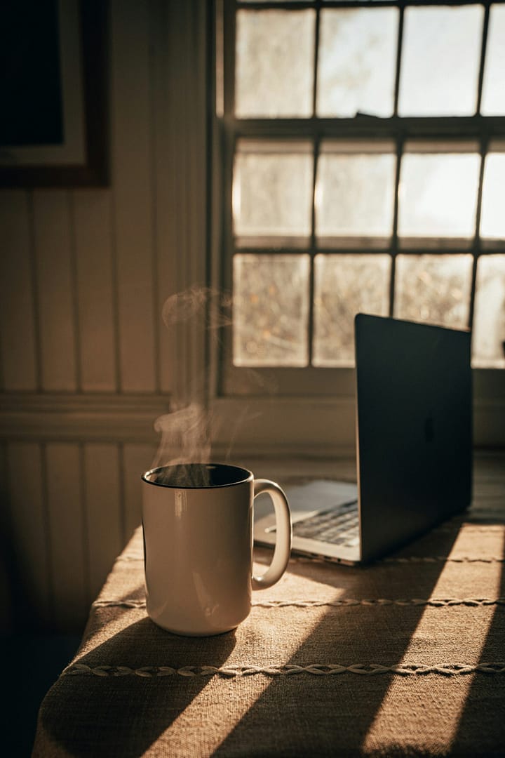 A cozy early morning scene with coffee cup, soft sunlight streaming through a kitchen window, and a peaceful start to a productive day.